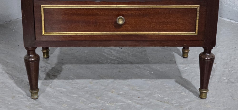 A tall, narrow dark mahogany chest of seven drawers with brass inlay banding, single knob handles, a brass gallery top, and turned tapered legs. View III