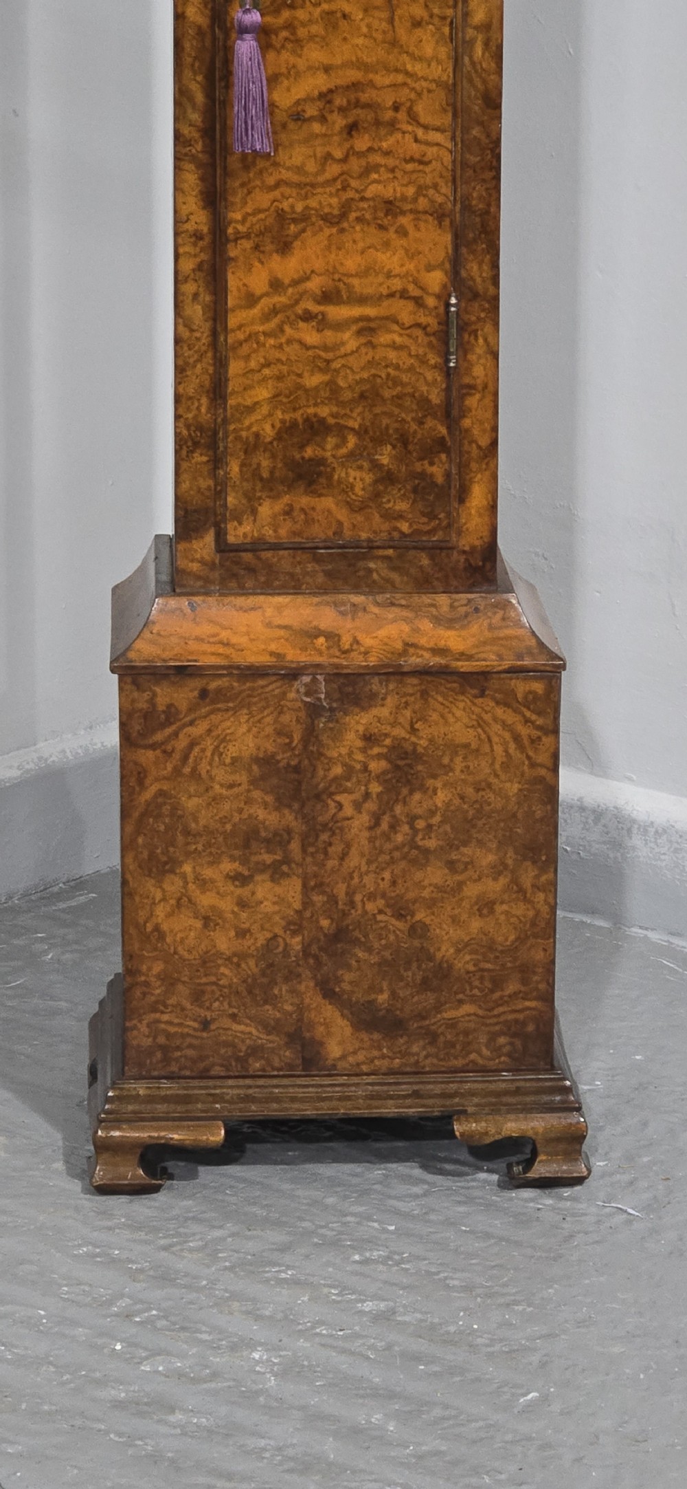 A slim floor-standing longcase clock crafted from figured burr walnut with a square brass dial and bracket feet. View VI