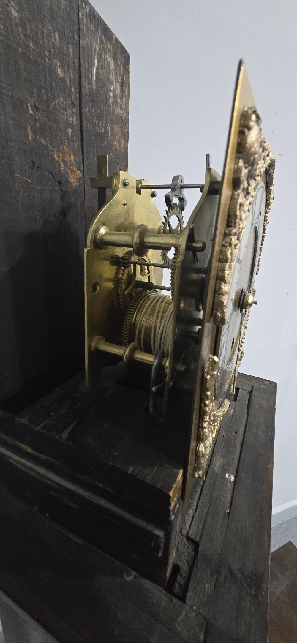 A slim floor-standing longcase clock crafted from figured burr walnut with a square brass dial and bracket feet. View XI