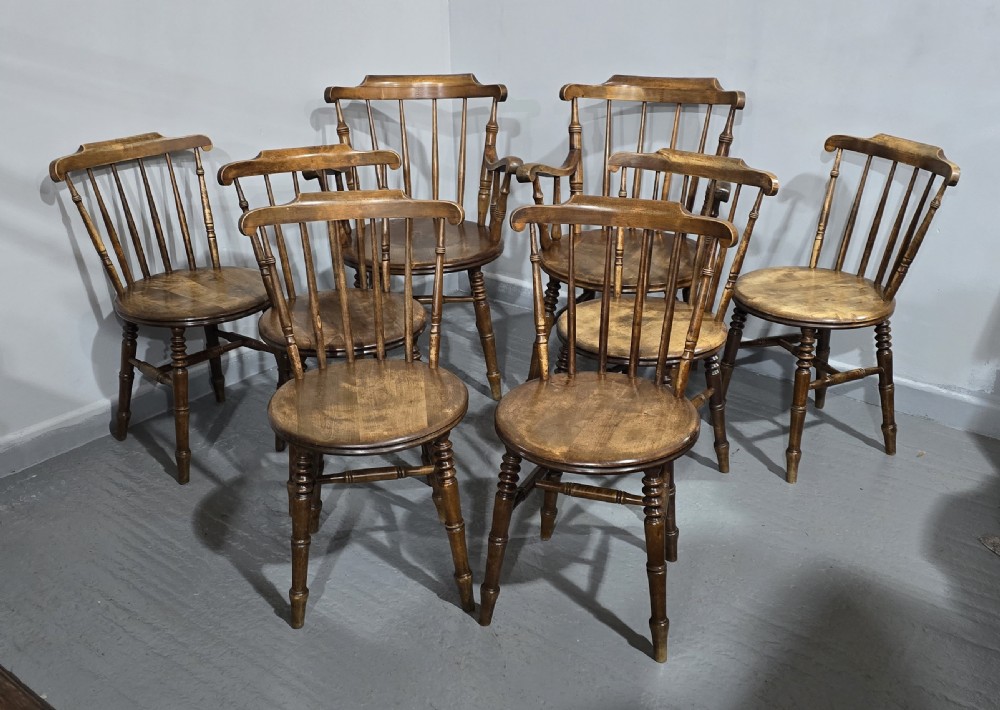 A set of eight antique warm brown wooden kitchen chairs with spindle backrests, turned legs, and contoured seats, including two armchairs. View II