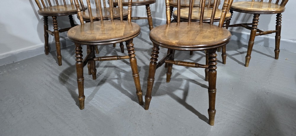 A set of eight antique warm brown wooden kitchen chairs with spindle backrests, turned legs, and contoured seats, including two armchairs. View III