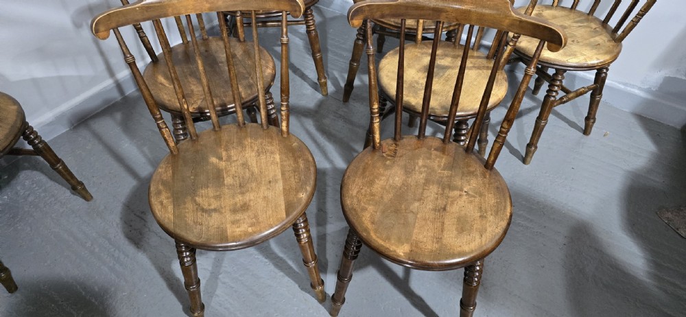 A set of eight antique warm brown wooden kitchen chairs with spindle backrests, turned legs, and contoured seats, including two armchairs. View V