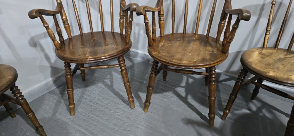 A set of eight antique warm brown wooden kitchen chairs with spindle backrests, turned legs, and contoured seats, including two armchairs. View X