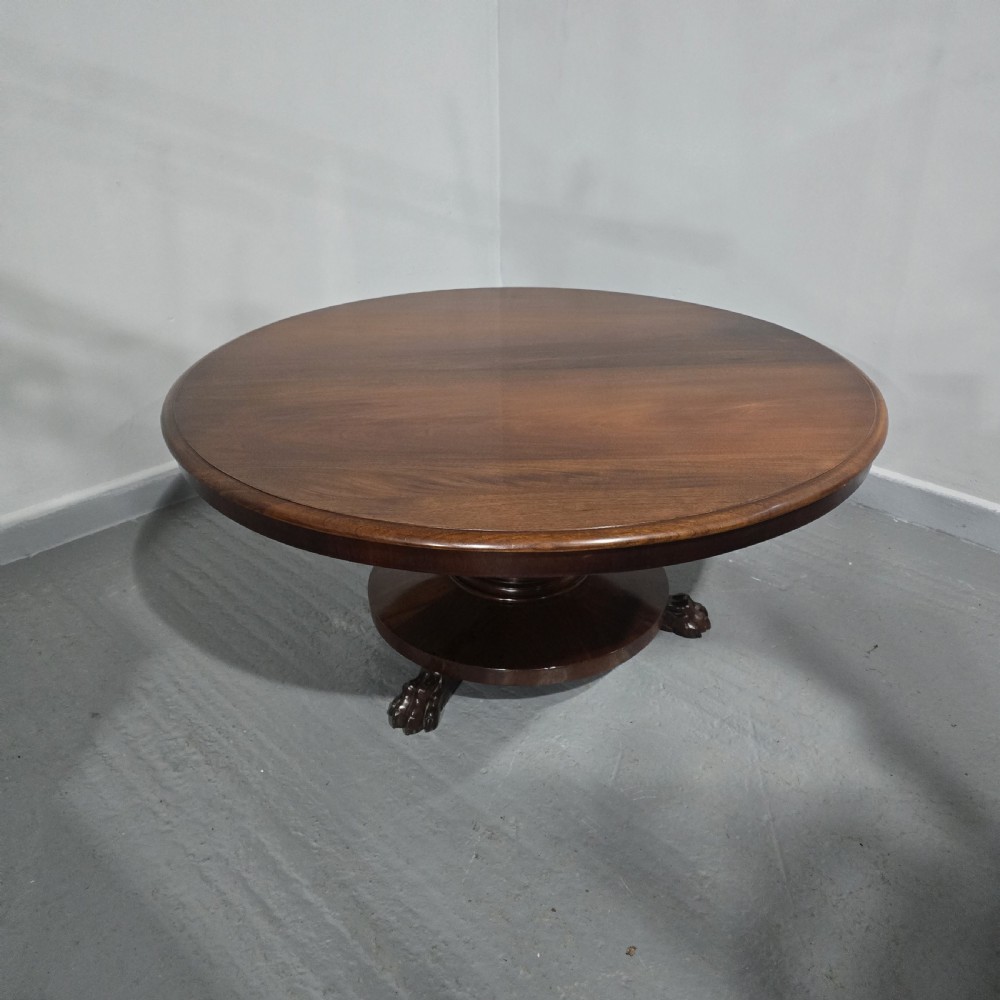 A low, circular mahogany coffee table featuring a smooth polished top supported by a central turned pedestal with carved claw feet. View II