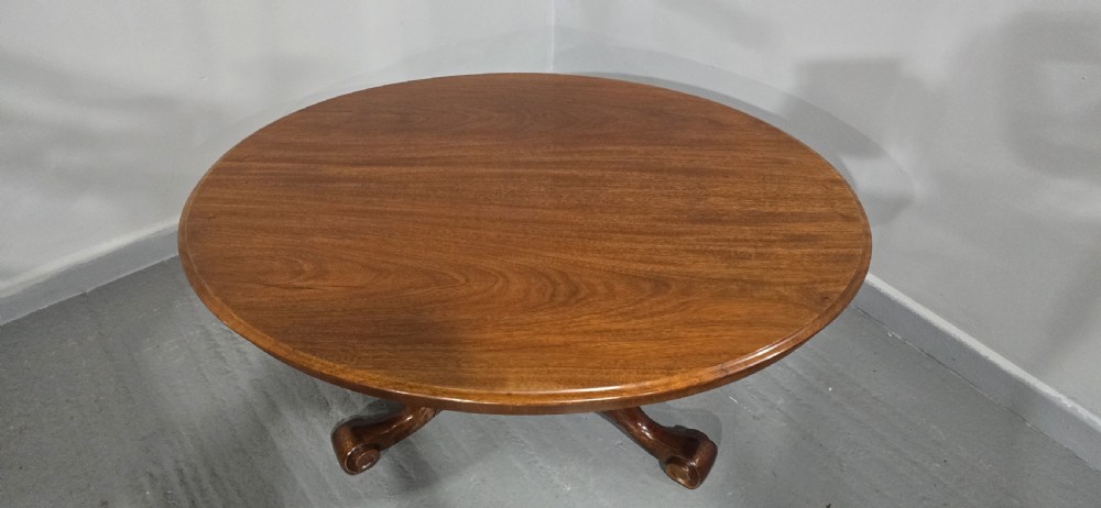 An oval mahogany coffee table featuring a polished surface, a central turned pedestal, and four carved cabriole legs terminating in scroll feet. View III