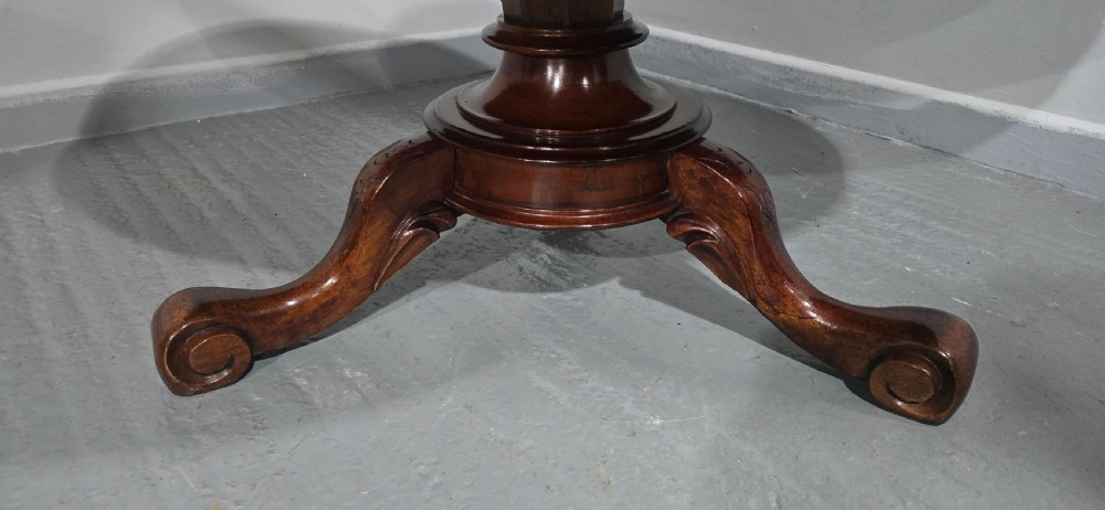 An oval mahogany coffee table featuring a polished surface, a central turned pedestal, and four carved cabriole legs terminating in scroll feet. View VI