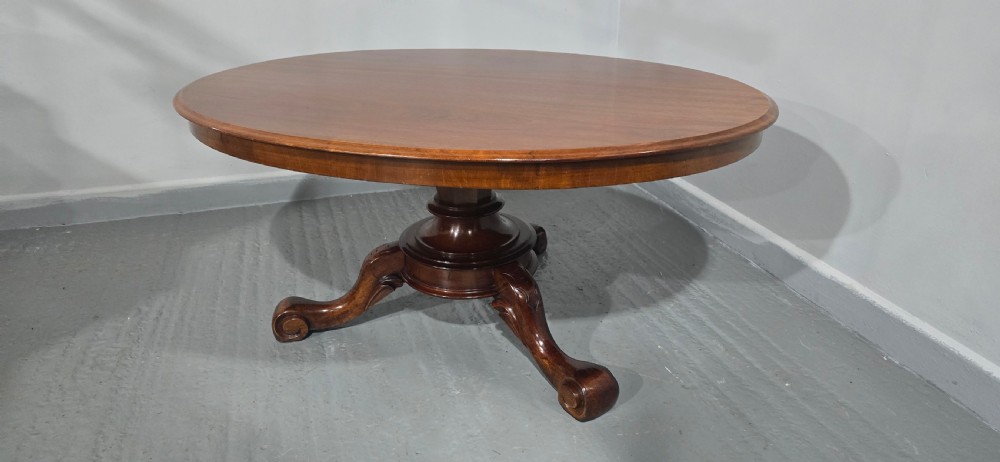 An oval mahogany coffee table featuring a polished surface, a central turned pedestal, and four carved cabriole legs terminating in scroll feet. View XI