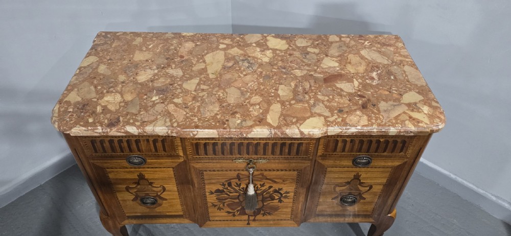 A French marquetry chest of drawers featuring inlaid urn and floral motifs, a contoured pink marble top, and cabriole legs. View V