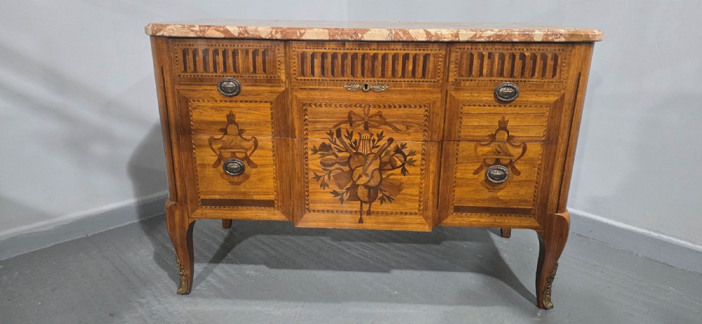 A French marquetry chest of drawers featuring inlaid urn and floral motifs, a contoured pink marble top, and cabriole legs. View XI