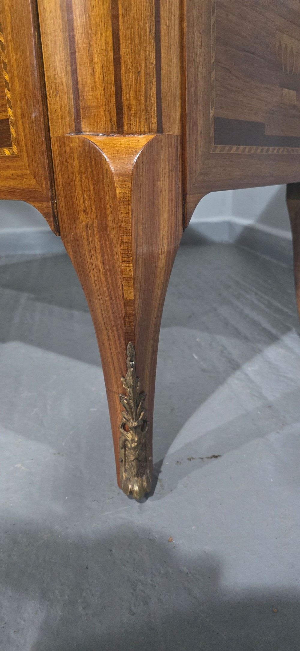 A French marquetry chest of drawers featuring inlaid urn and floral motifs, a contoured pink marble top, and cabriole legs. View XII