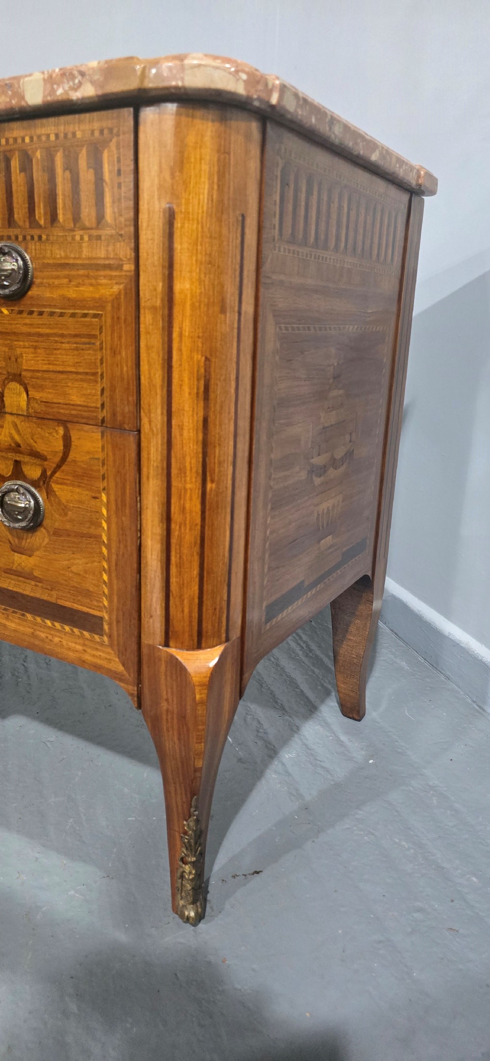 A French marquetry chest of drawers featuring inlaid urn and floral motifs, a contoured pink marble top, and cabriole legs. View XIII