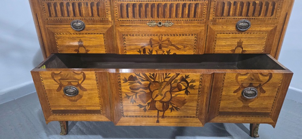 A French marquetry chest of drawers featuring inlaid urn and floral motifs, a contoured pink marble top, and cabriole legs. View XIV