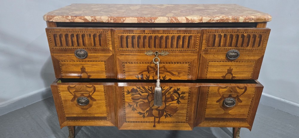A French marquetry chest of drawers featuring inlaid urn and floral motifs, a contoured pink marble top, and cabriole legs. View XV