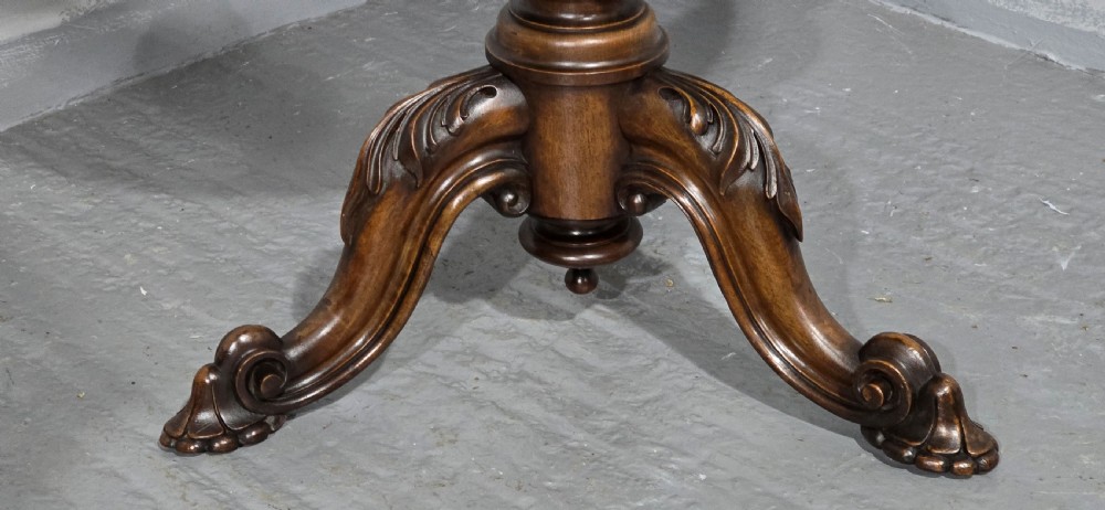 A circular Victorian walnut library table featuring a reddish-brown leather inset top, turned central pedestal stem, and carved tripod legs with scroll feet. View IV