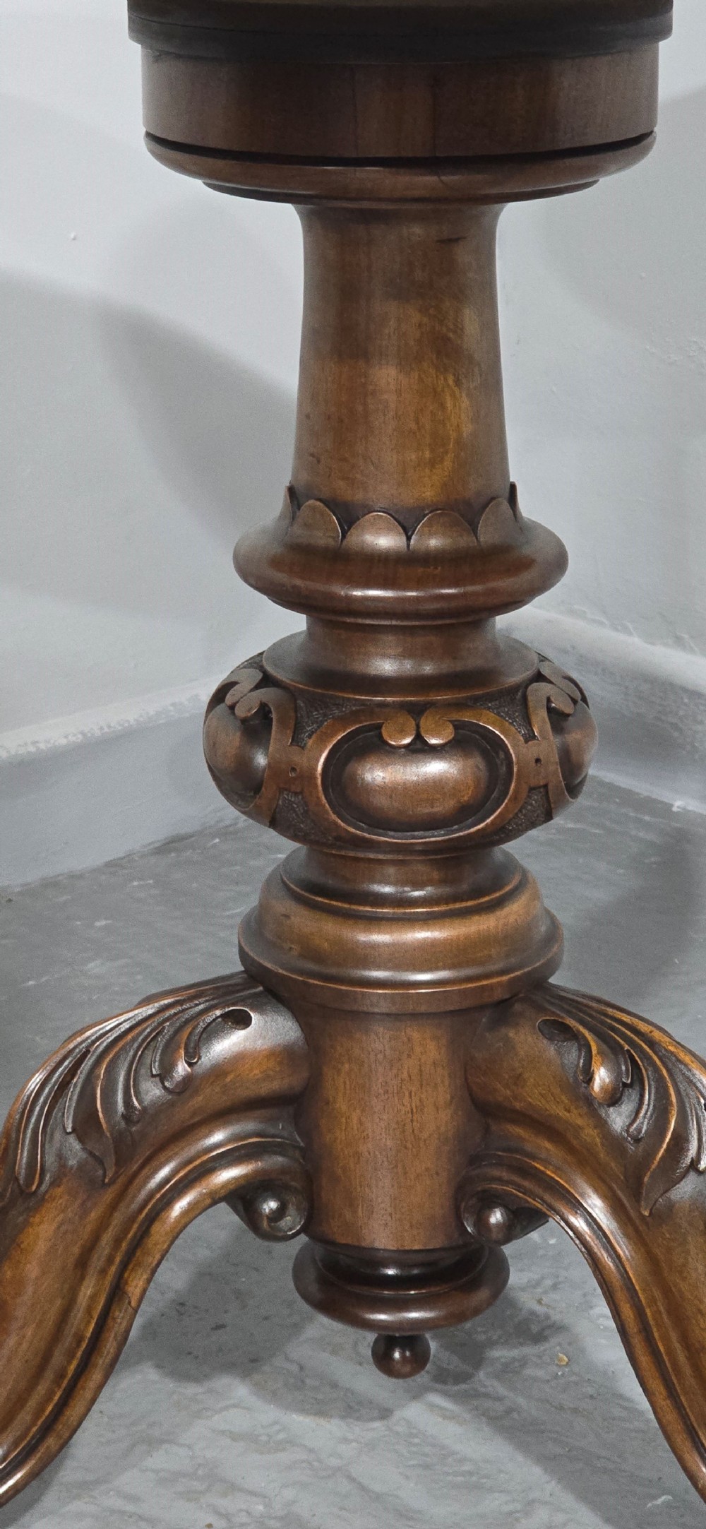 A circular Victorian walnut library table featuring a reddish-brown leather inset top, turned central pedestal stem, and carved tripod legs with scroll feet. View V