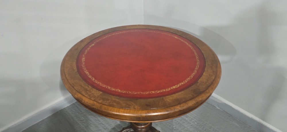 A circular Victorian walnut library table featuring a reddish-brown leather inset top, turned central pedestal stem, and carved tripod legs with scroll feet. View IX