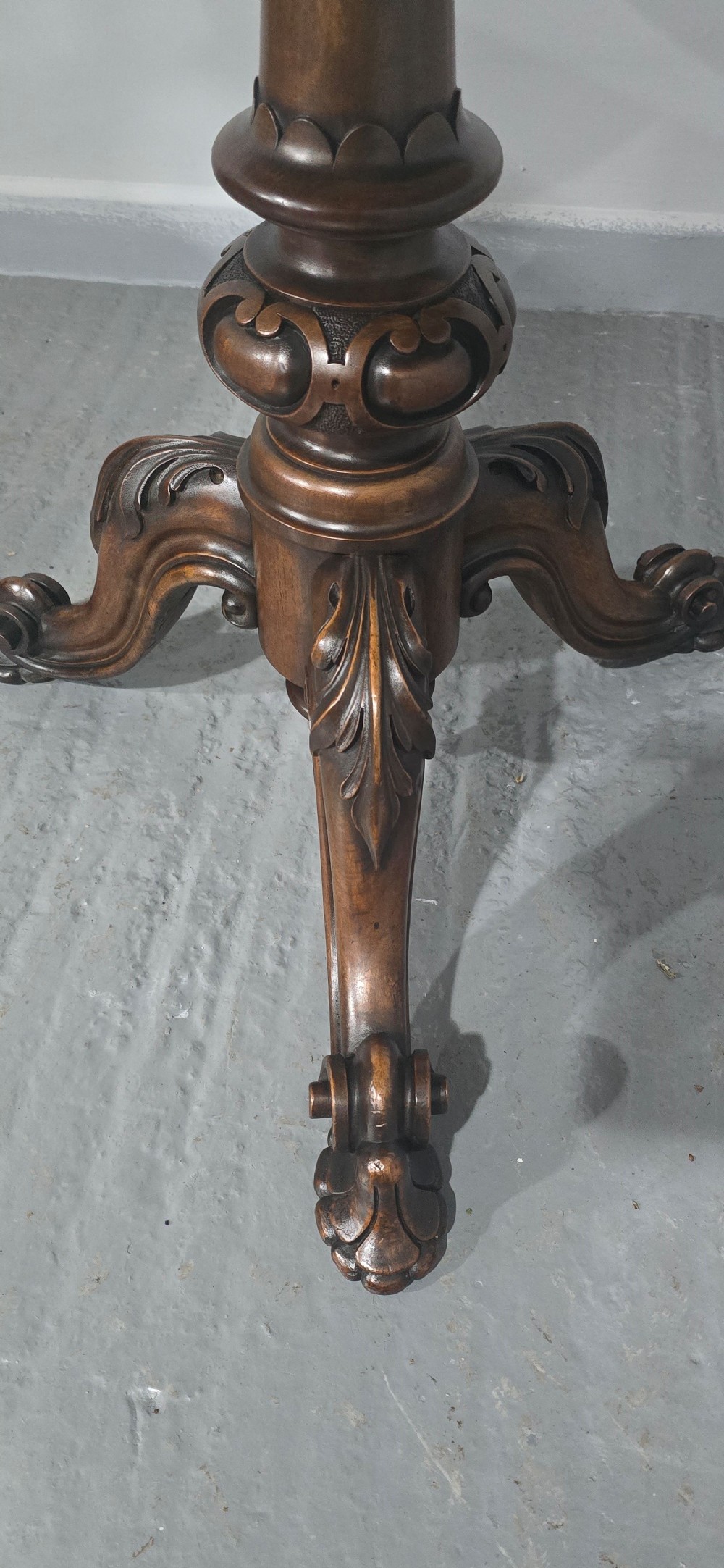 A circular Victorian walnut library table featuring a reddish-brown leather inset top, turned central pedestal stem, and carved tripod legs with scroll feet. View X