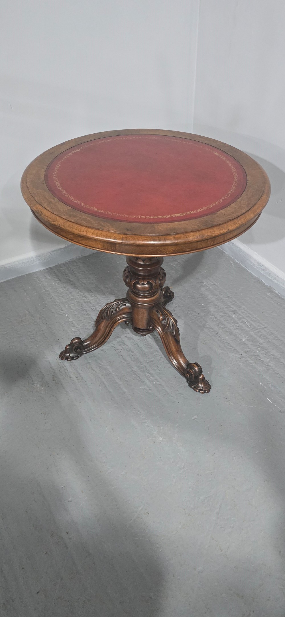 A circular Victorian walnut library table featuring a reddish-brown leather inset top, turned central pedestal stem, and carved tripod legs with scroll feet. View XI