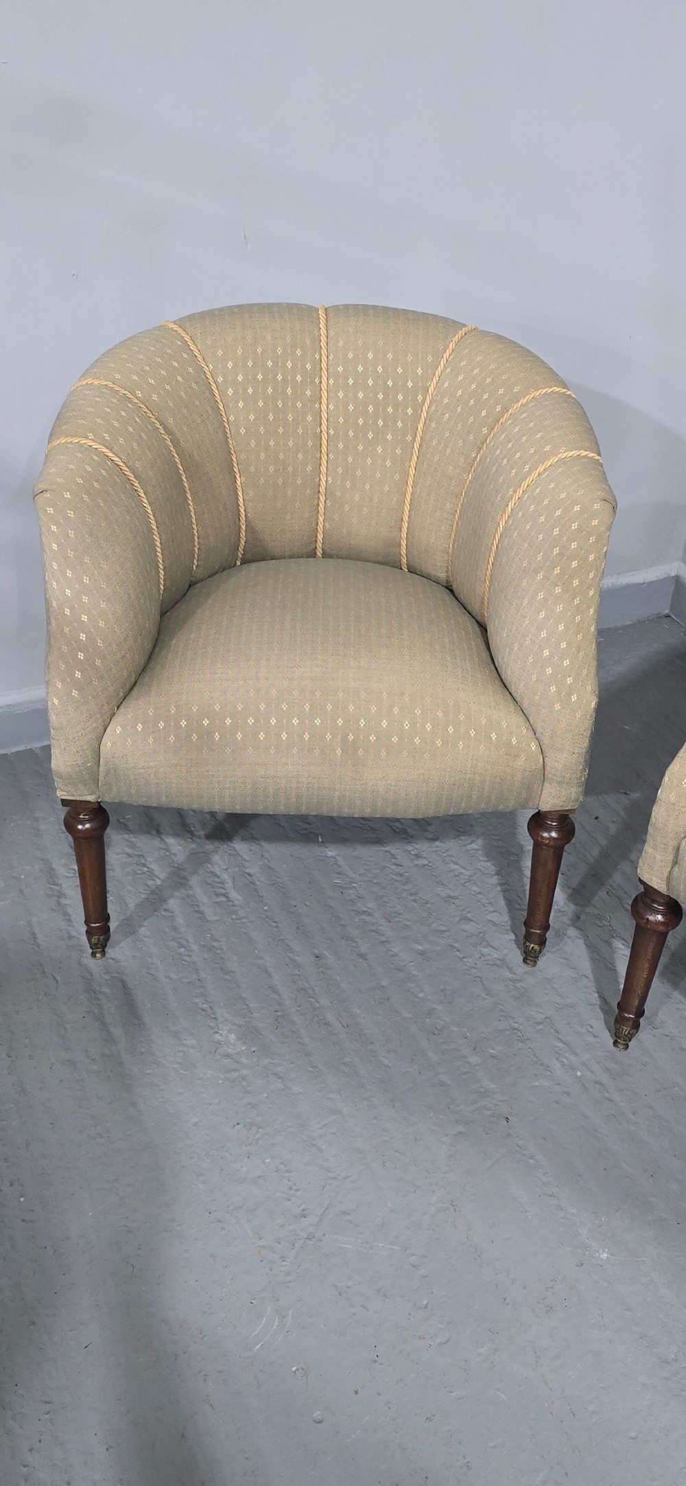A pair of French walnut tub chairs upholstered in light beige patterned fabric with channelled backrests and turned wooden legs. View V