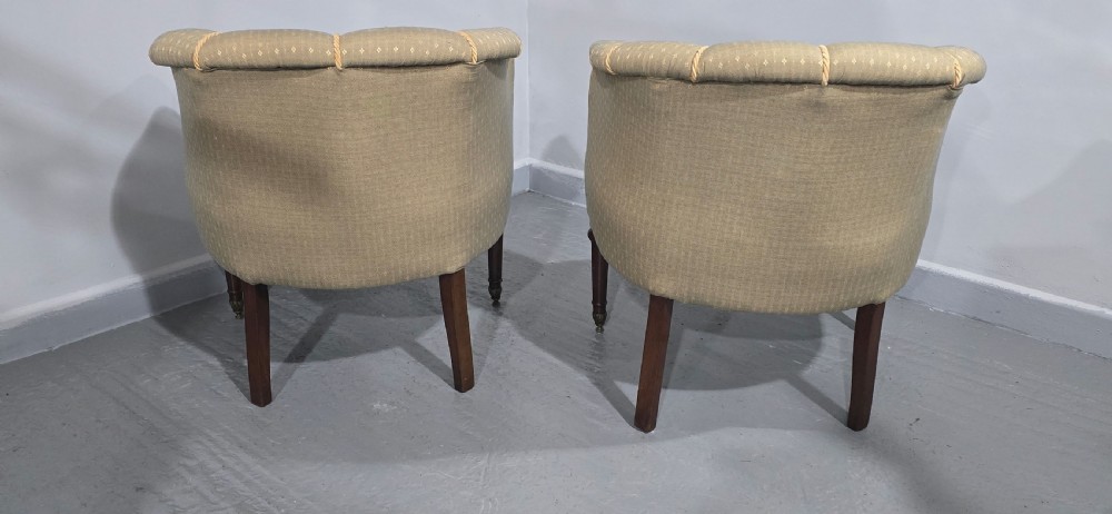 A pair of French walnut tub chairs upholstered in light beige patterned fabric with channelled backrests and turned wooden legs. View X