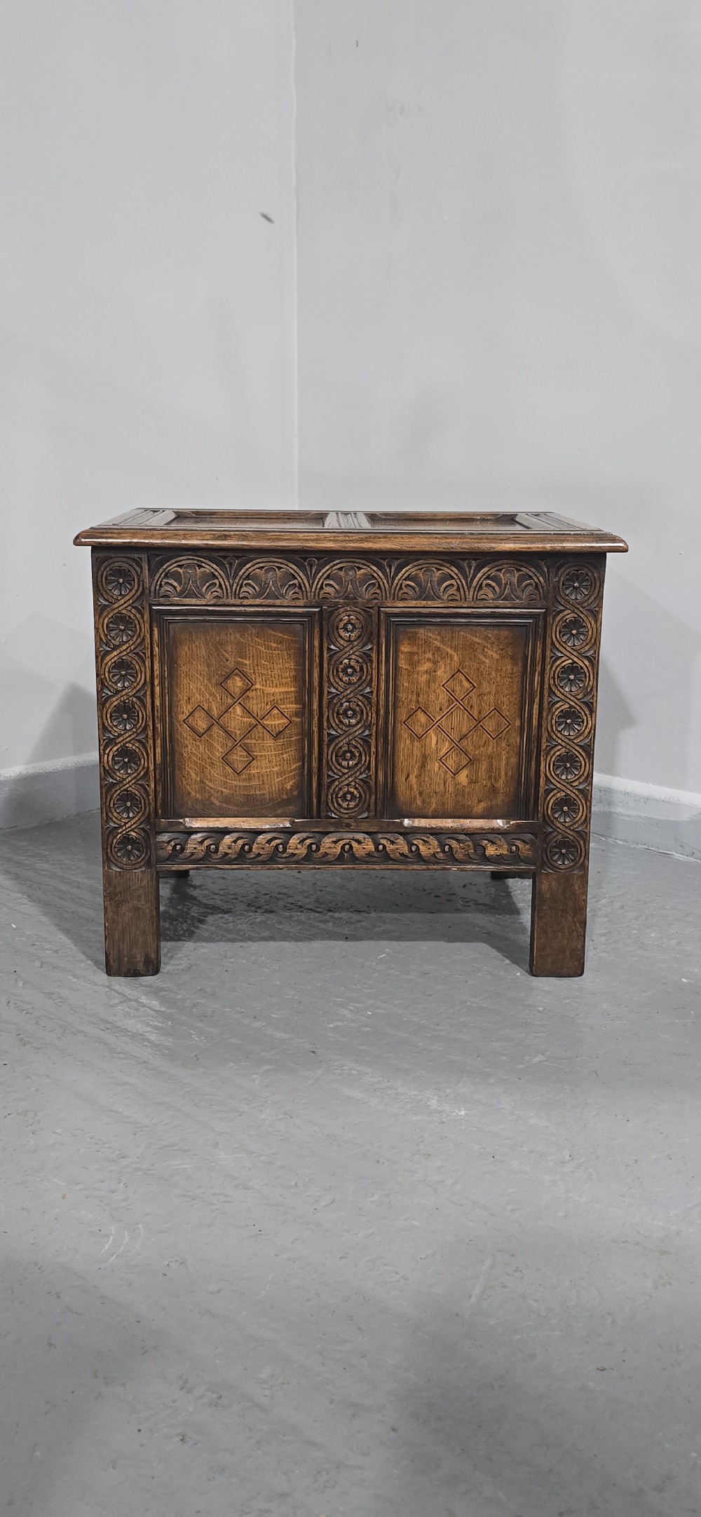 A small dark oak coffer with carved detail, geometric panel inlays, and floral guilloche borders. View III
