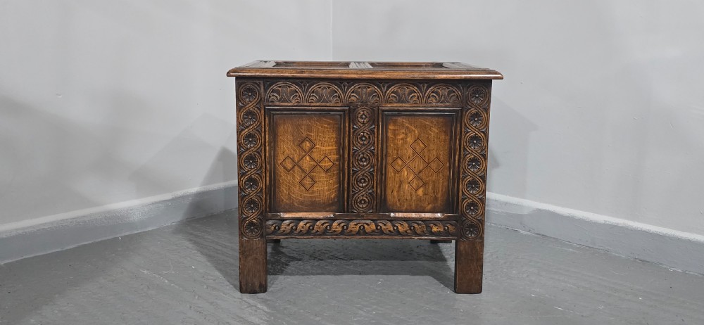 A small dark oak coffer with carved detail, geometric panel inlays, and floral guilloche borders. View IV