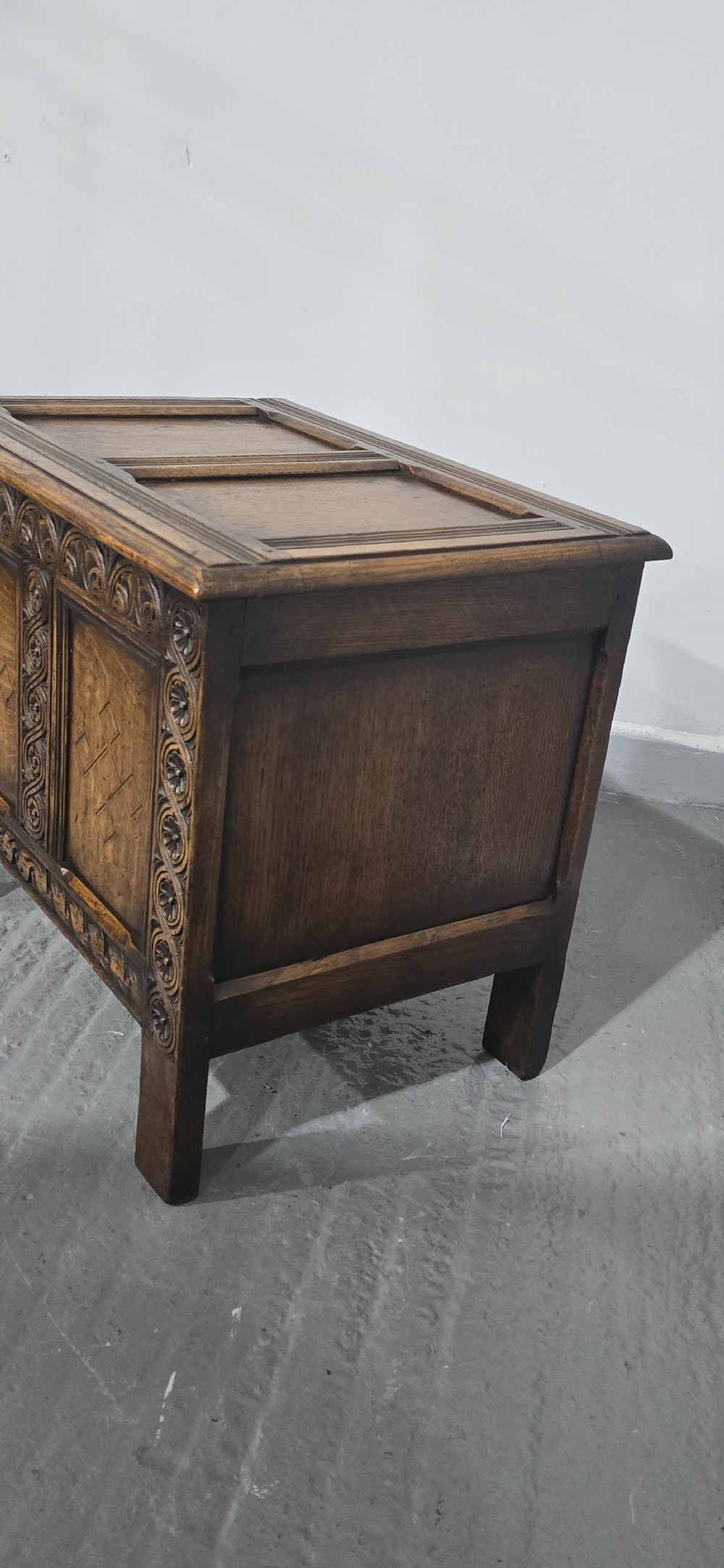A small dark oak coffer with carved detail, geometric panel inlays, and floral guilloche borders. View VI