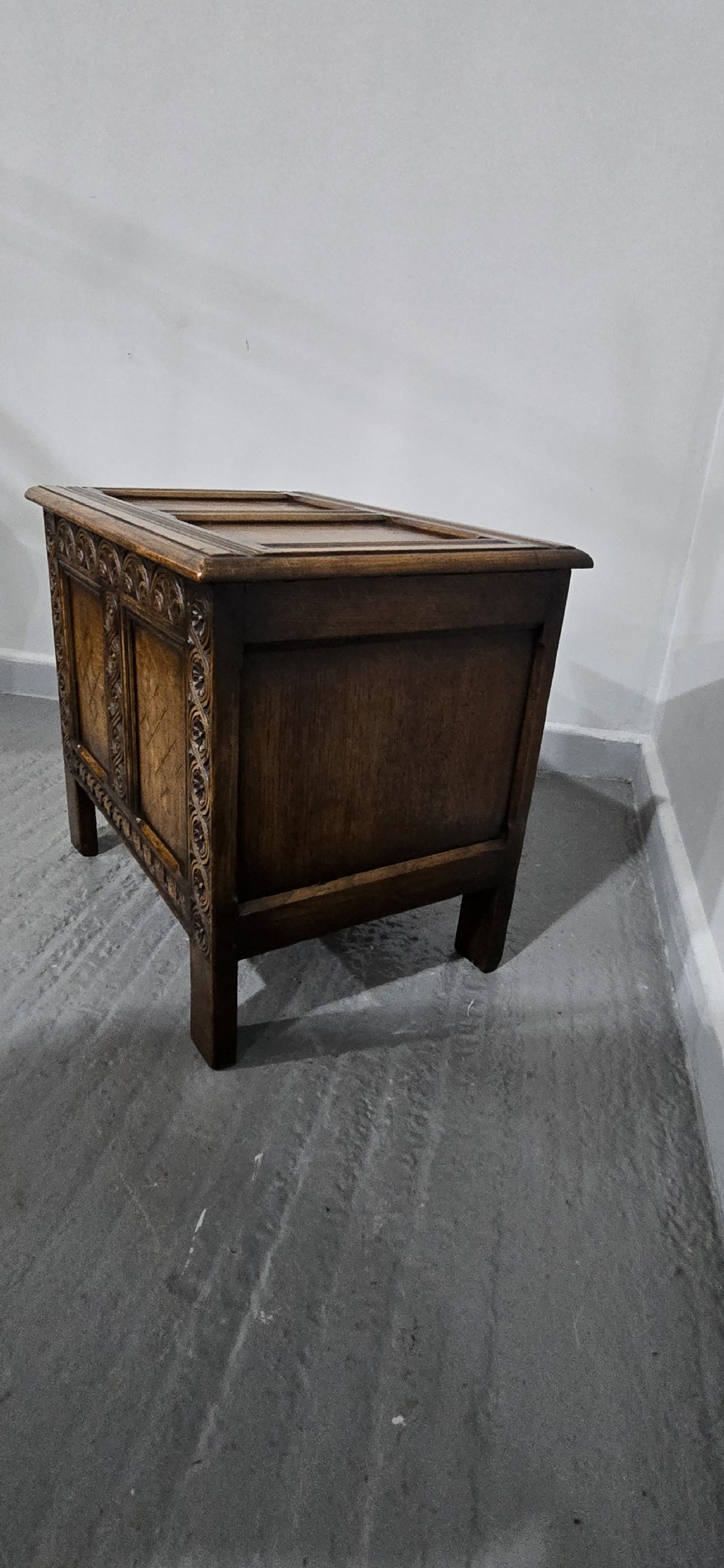 A small dark oak coffer with carved detail, geometric panel inlays, and floral guilloche borders. View VII