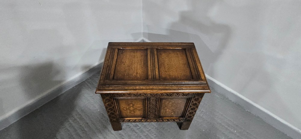 A small dark oak coffer with carved detail, geometric panel inlays, and floral guilloche borders. View VIII