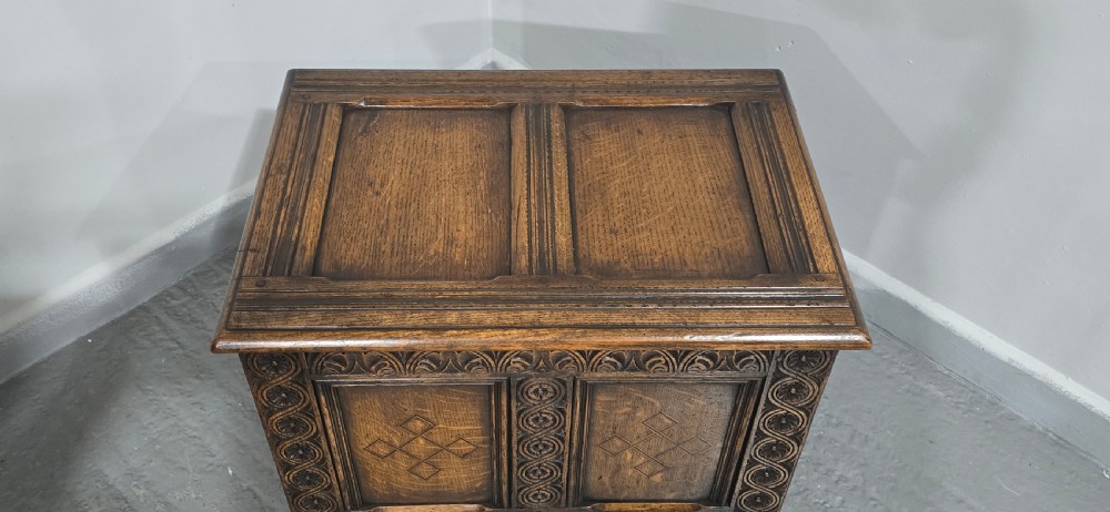 A small dark oak coffer with carved detail, geometric panel inlays, and floral guilloche borders. View IX