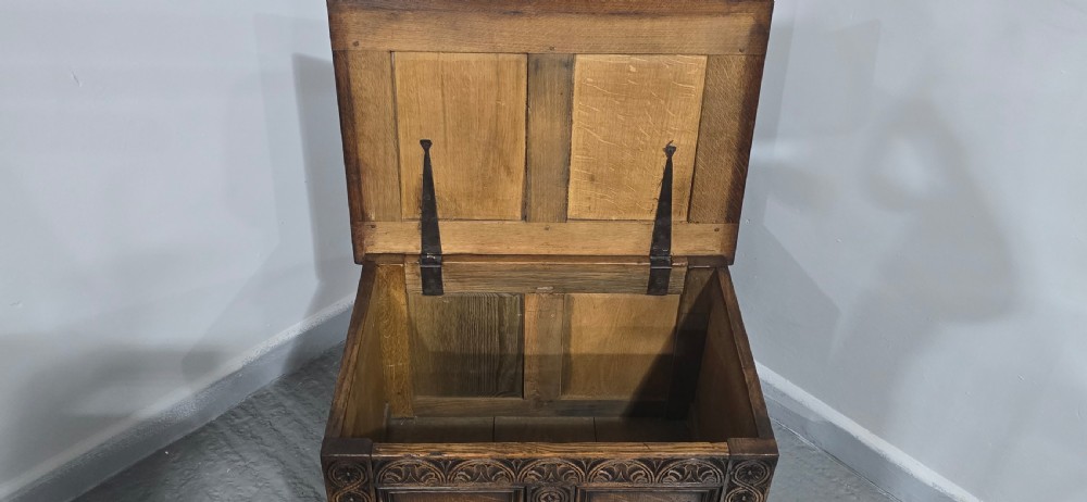 A small dark oak coffer with carved detail, geometric panel inlays, and floral guilloche borders. View X