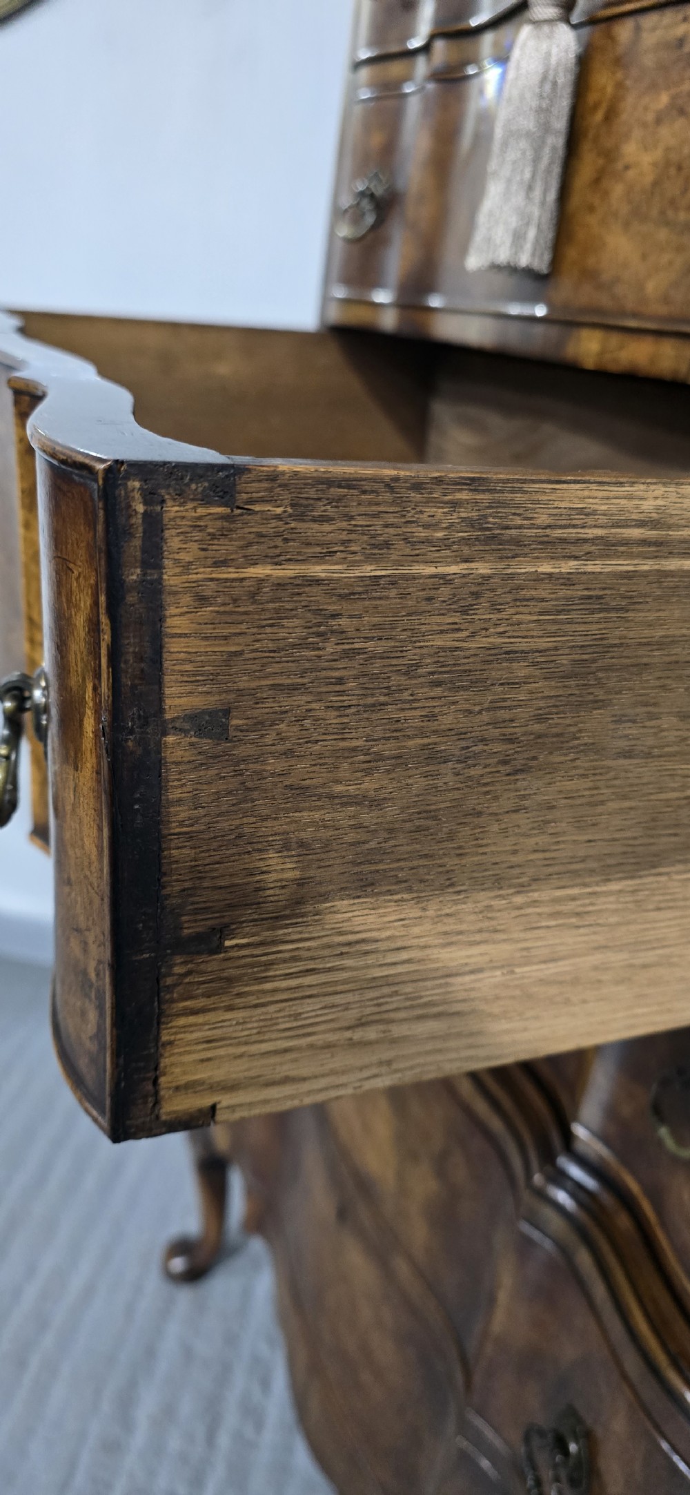 A tall Queen Anne burr walnut chest on stand featuring a serpentine contoured front with six drawers, brass drop handles, and carved cabriole legs. View X