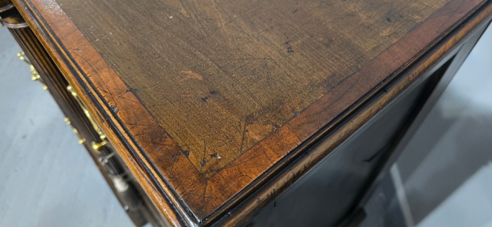 A dark oak Georgian breakfront dresser base featuring brass swan-neck handles, three central drawers, and two outer cupboard doors set on bracket feet. View VI