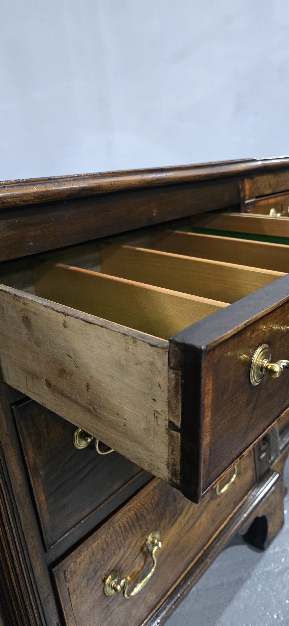A dark oak Georgian breakfront dresser base featuring brass swan-neck handles, three central drawers, and two outer cupboard doors set on bracket feet. View IX