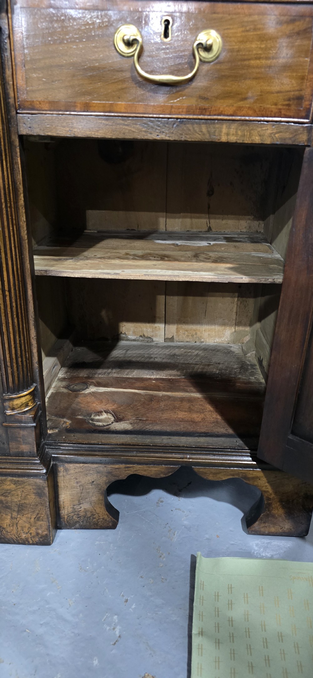 A dark oak Georgian breakfront dresser base featuring brass swan-neck handles, three central drawers, and two outer cupboard doors set on bracket feet. View XI
