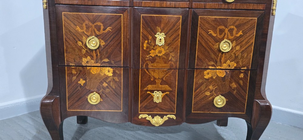 A French Louis XV style marquetry commode chest featuring floral inlays, gilt-bronze mounts, cabriole legs, and a beige marble top. View IV