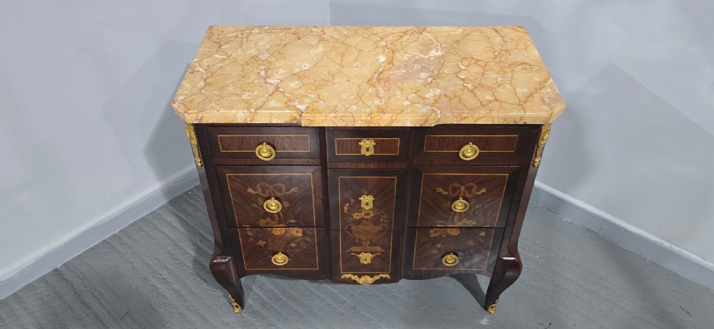 A French Louis XV style marquetry commode chest featuring floral inlays, gilt-bronze mounts, cabriole legs, and a beige marble top. View X