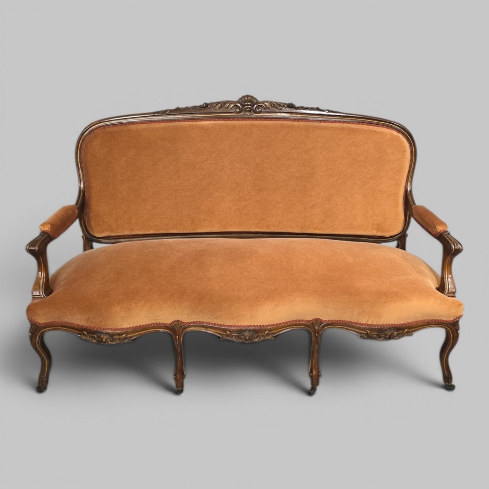A French Louis XV style carved walnut settee with warm amber velvet upholstery, serpentine seat rail, and cabriole legs.