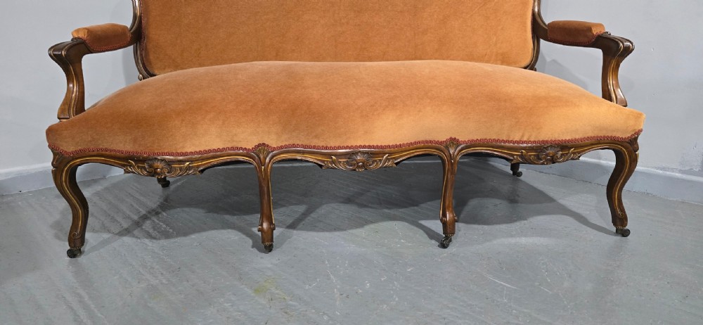 A French Louis XV style carved walnut settee with warm amber velvet upholstery, serpentine seat rail, and cabriole legs. View IV