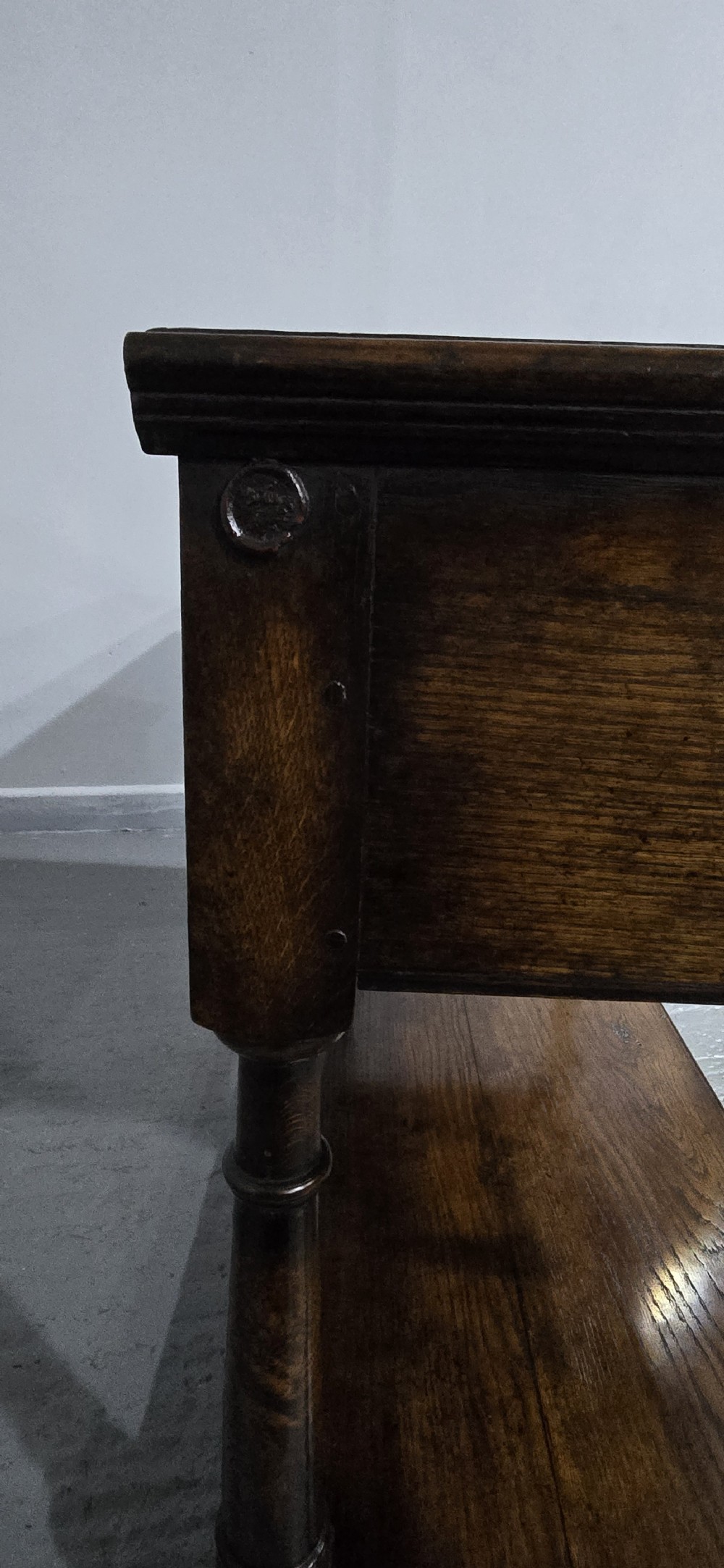 An antique dark oak dresser base featuring four panelled drawers with brass drop handles above turned supports and an open lower shelf. View XV