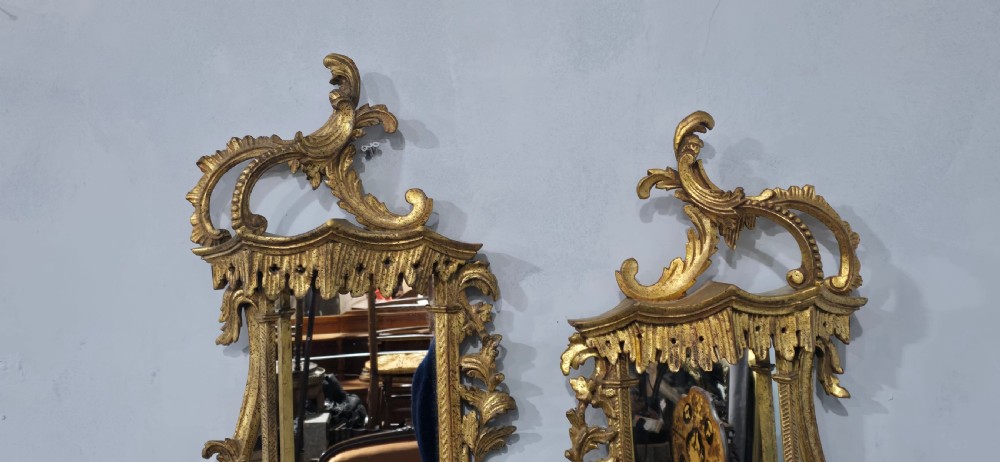 A pair of carved giltwood wall mirrors featuring Chinese Chippendale pagoda crestings and Rococo C-scroll motifs. View VI