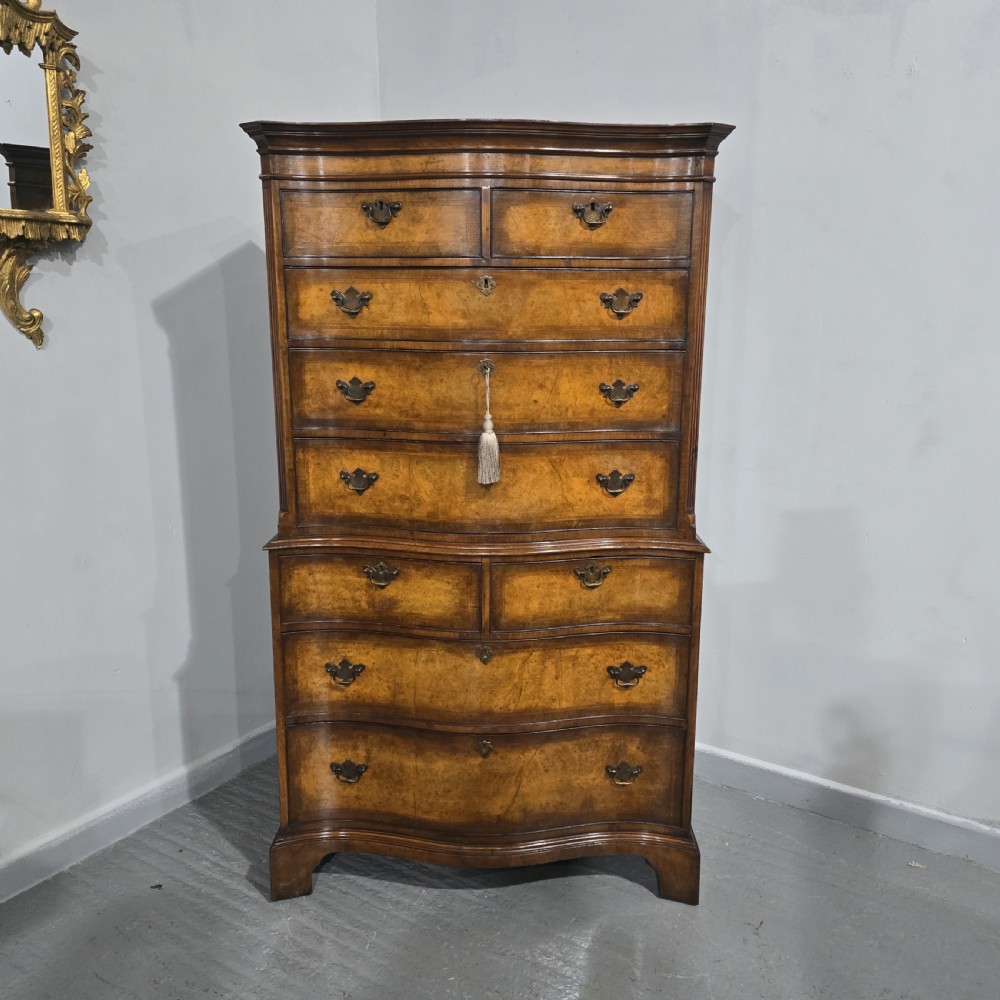 A tall two-part burr walnut chest on chest featuring a curved serpentine front, multi-drawer arrangement with brass drop handles, and bracket feet. View II