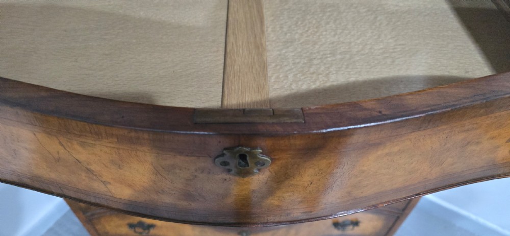 A tall two-part burr walnut chest on chest featuring a curved serpentine front, multi-drawer arrangement with brass drop handles, and bracket feet. View XI