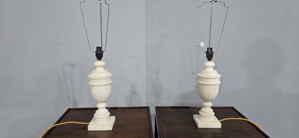 A pair of carved off-white marble urn-form table lamps with square plinth bases and pleated cream fabric shades. View IV