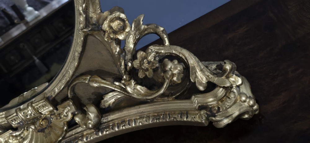 An oval gilt metal dressing table mirror with a top floral wreath cresting and an acanthus leaf scroll base. View IX