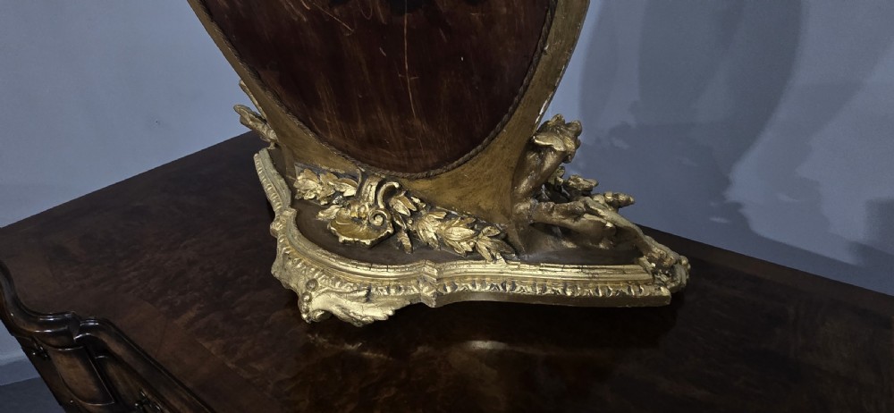 An oval gilt metal dressing table mirror with a top floral wreath cresting and an acanthus leaf scroll base. View XV