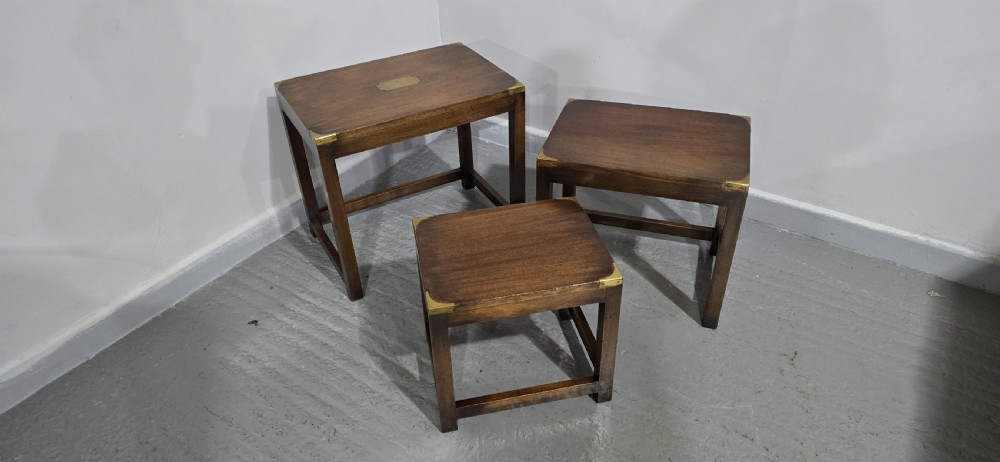 A set of three graduated mahogany nest tables with brass corner mounts and central plaque inlays stacked on straight square legs. View IV