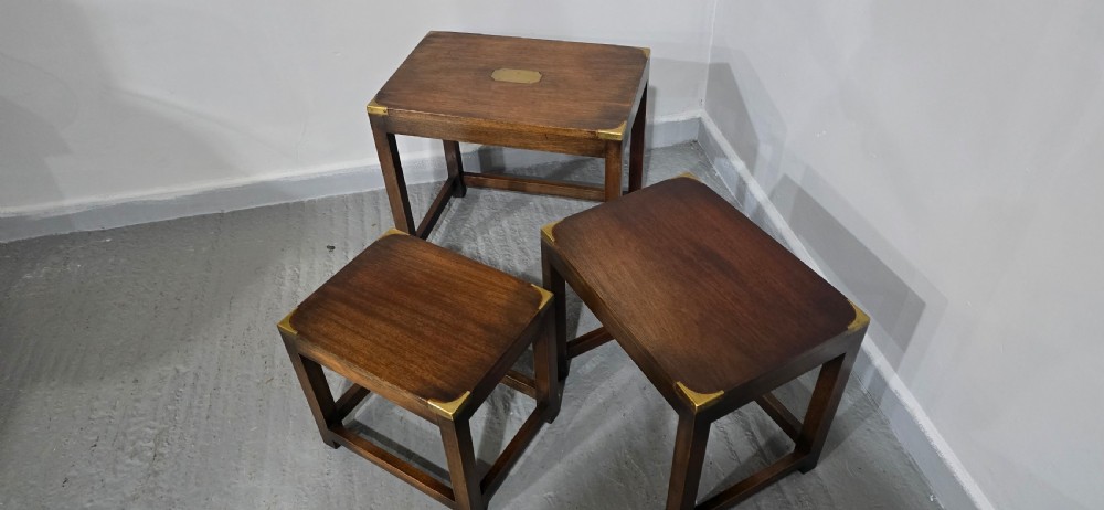 A set of three graduated mahogany nest tables with brass corner mounts and central plaque inlays stacked on straight square legs. View VI