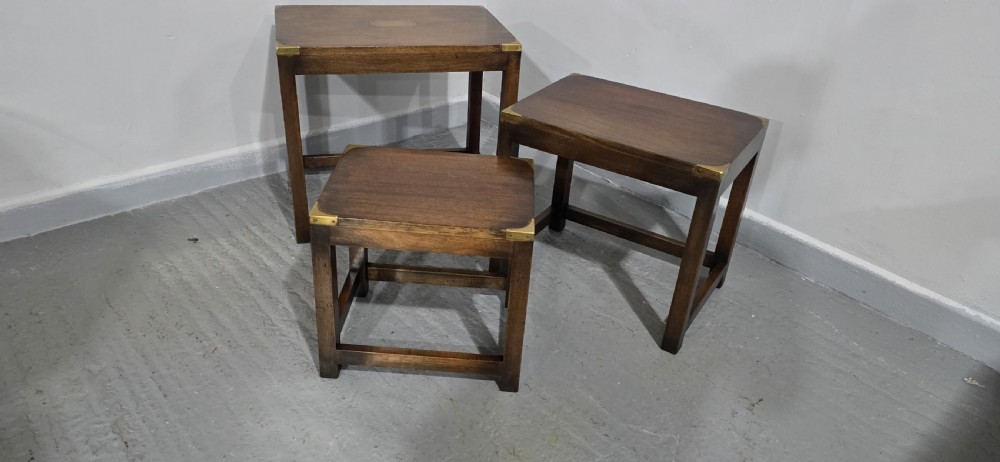 A set of three graduated mahogany nest tables with brass corner mounts and central plaque inlays stacked on straight square legs. View VII