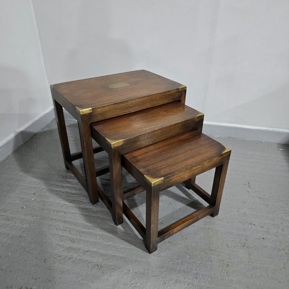 A set of three graduated mahogany nest tables with brass corner mounts and central plaque inlays stacked on straight square legs. View VIII